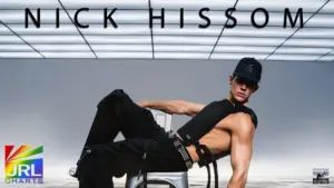 Nick Hissom posing in Hot Boy Things music video wearing black outfit under illuminated ceiling