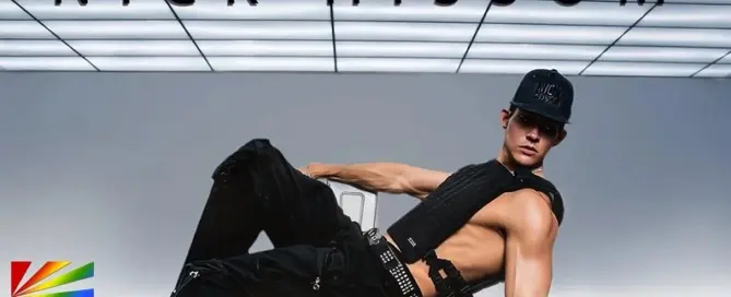 Nick Hissom posing in Hot Boy Things music video wearing black outfit under illuminated ceiling